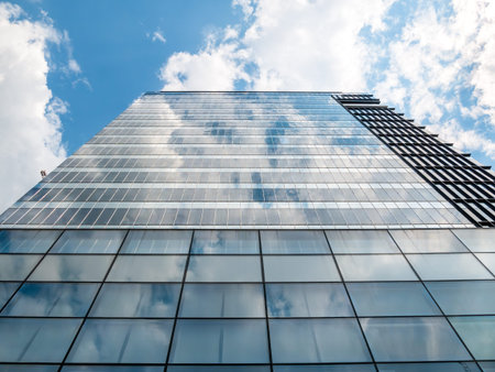 Modern skyscraper in business district with the sky reflecting in the glass windows.