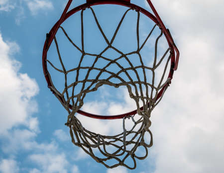 Close up with a basketball hoop against blue and cloudy sky.の写真素材