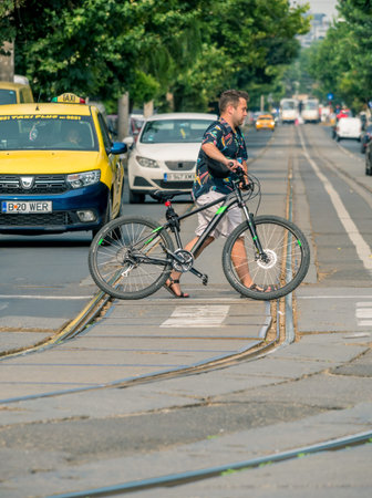 Man walking the bike across the street as a pedestrian. Man with his bicycle crossing the tram...