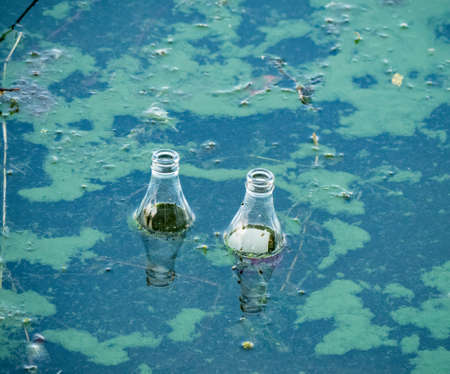 Two glass bottles floating on the surface of water.の写真素材