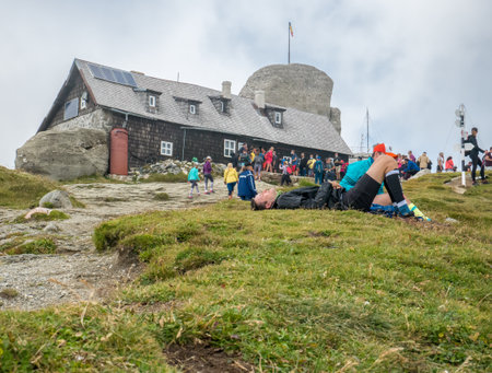 Busteni/Romania - 08.22.2020: Crowded weekend day on Omu Peak, the highest peak in Bucegi Mountains. Man lying on the grass and smiling.のeditorial素材