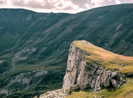 Scenic landscape in Bucegi Mountains with a huge rock formation against a dark cloudy sky.の写真素材