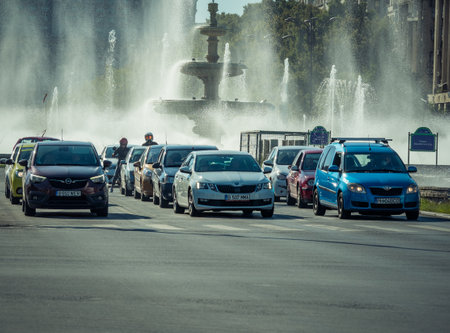 Bucharest/Romania - 09.05.2020: Unirii Square in the center of Bucharest with cars at the stoplight and water fountains in the background.のeditorial素材