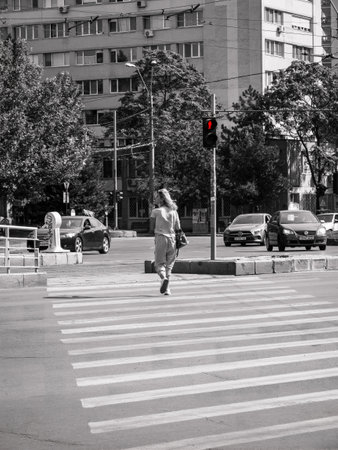 Bucharest/Romania - 07.15.2020: Girl crossing the street while the stoplight is showing the red man. Pedestrian jaywalking.のeditorial素材