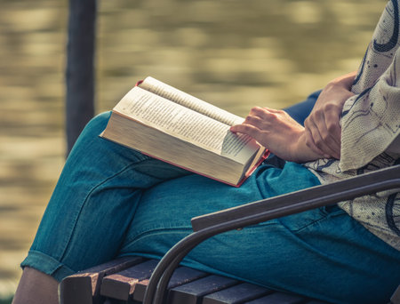 Woman sitting on a bench in the park and reading a book