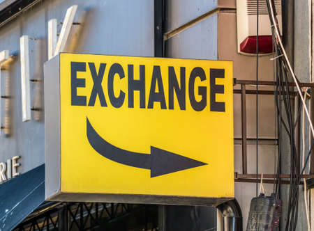 Yellow exchange sign board with a black arrow pointing in the direction of the store.の写真素材