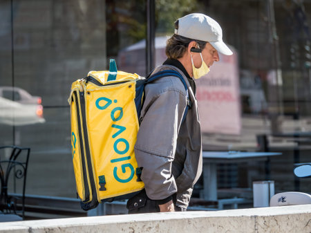 Bucharest/Romania - 10.25.2020: Glovo courier carrying the yellow delivery bag