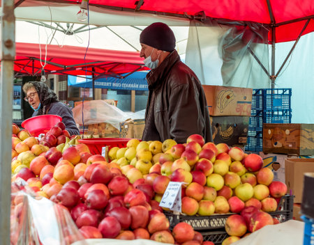 Bucharest/Romania - 11.20.2020: Man selling apples at a fruit stall . Fruit and vegetables market in Bucharest.のeditorial素材