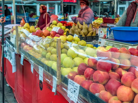 Bucharest/Romania - 11.20.2020: Woman selling apples at a fruit stall . Fruit and vegetables market in Bucharest.のeditorial素材