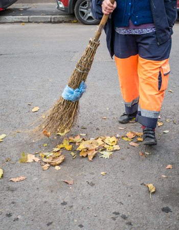 Bucharest/Romania - 11.08.2020: Street sweeper or garbage man broomig the leaves from the street or sidewalkのeditorial素材