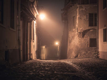 Night scene from Sighisoara Citadel with cobblestone streets, old medieval buildings and a lamp postの写真素材