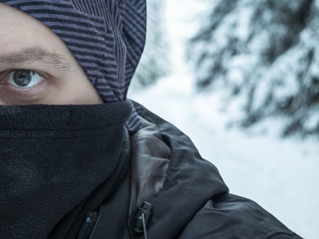 Half face detailed portrait of a hiker in a cold winter landscape
