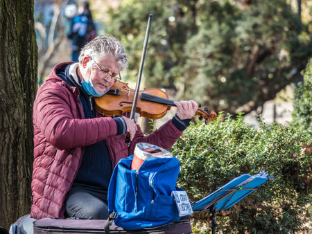 Bucharest, Romania - 02.12.2021: Street artist busker playing violin in Cismigiu park, Bucharest.のeditorial素材