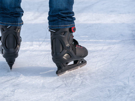 Close up with a man or a woman with skates on ice. Ice skating recreational activity.
