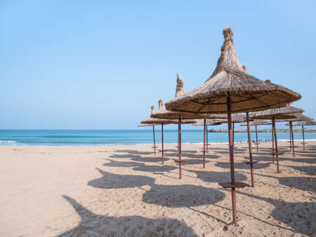 Summer landscape with straw umbrellas on the beach in Mangalia or Mamaia. Beach at the Black Sea in Romania.の写真素材