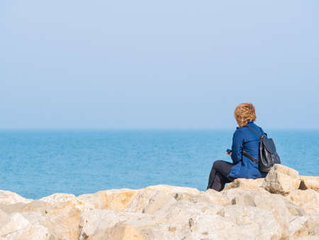 Woman sitting on a rock on the beach of the Black Sea and looking at the horizon.の写真素材
