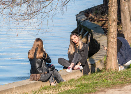Bucharest, Romania - 03.26.2021: Attractive young girl posing on the edge of the lake in King Mihai I Park (herestrau)のeditorial素材