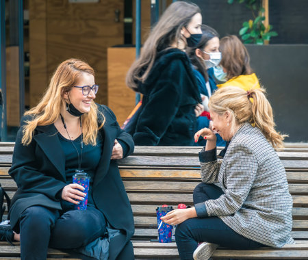 Bucharest, Romania - 03.13.2021: Two women on a bench in the center of Bucharest having a coffee and laughing.のeditorial素材