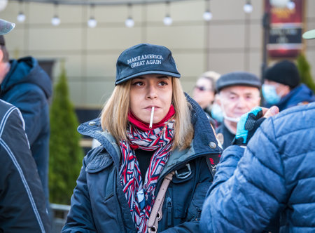 Bucharest, Romania - 03.13.2021: Girl or woman with a cigarette between her lips and a hat with "Make America great again " print.のeditorial素材