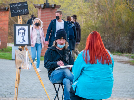Bucharest, Romania - 03.26.2021: Sreet artist cartoonist or painter making portraits to people in Herestrau park (Kink MIhai I), Bucharestのeditorial素材
