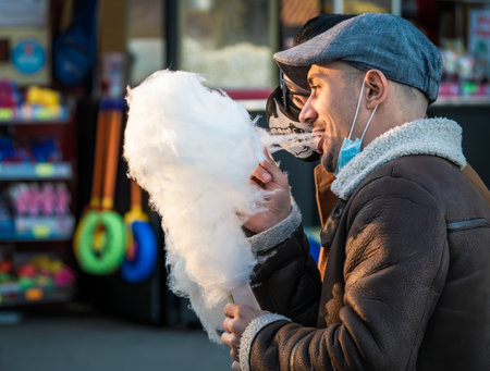 Bucharest, Romania - 03.26.2021: Happy smiling man eating sugar cotton wool on a stick in King Mihai park (Herestrau), in Bucharestのeditorial素材