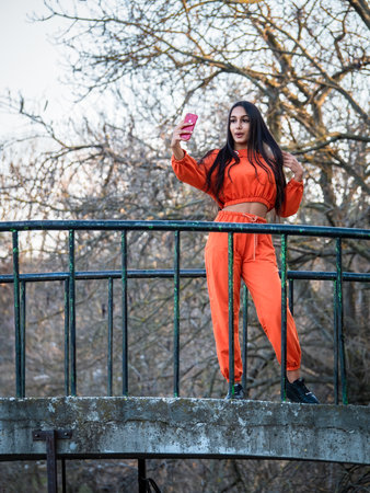 Bucharest, Romania - 03.26.2021:Young girl dressed in orange clothestaking a selfie to post on social media networksのeditorial素材