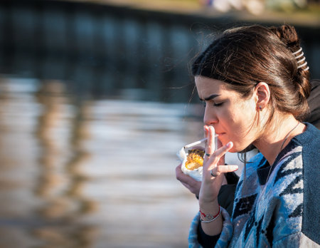 Bucharest, Romania - 03.26.2021: Young girl smoking a slim cigarette outdoorのeditorial素材