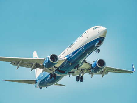 Otopeni, Romania - 05.08.2021: Blue Air Boeing 737-82R (YR-BMK) flying against blue sky. Airplane arriving at Henry Coanda International Airport.のeditorial素材