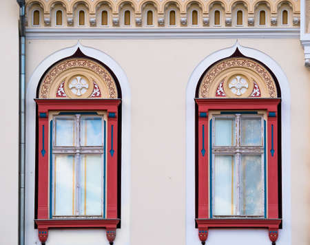 Detail with a beautiful restored old building in timisoara Romania. Architectural detail of two colred wooden framed windowの写真素材