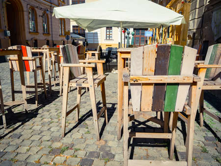 Wooden chairs and table on a cobbled street. Outdoor restaurant terrace cafe in the center of Timisoara city, Romania.の写真素材