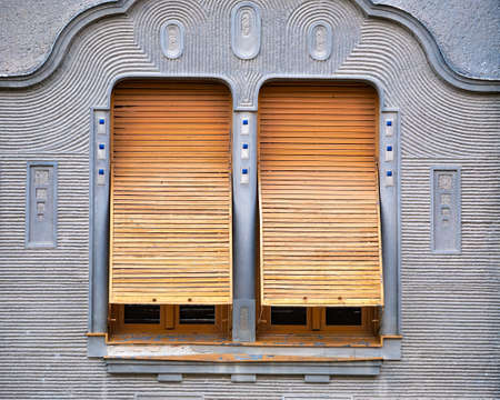 Detail of two windows with old wooden or metal shutters on a grey wallの写真素材