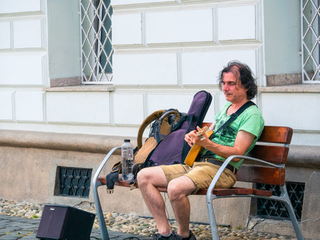 Timisoara, Romania - 06.19.2021: Street artist on a bench with a guitar playing and singing in the...