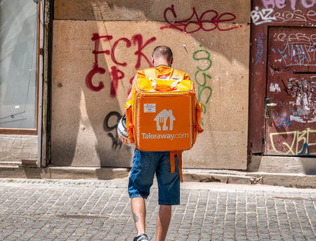 Timisoara, Romania - 06.25.2020: Take away.com courier carrying the orange delivery bagのeditorial素材