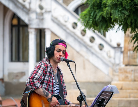 Timisoara, Romania - 06.19.2021: Young street artist with a guitar playing and singing in the center of Timisoaraのeditorial素材
