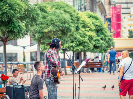 Timisoara, Romania - 06.19.2021: Young street artist with a guitar playing and singing in the center of Timisoaraのeditorial素材