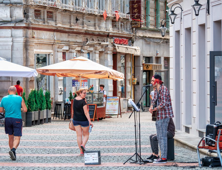 Timisoara, Romania - 06.19.2021: Young street artist with a guitar playing and singing in the center of Timisoaraのeditorial素材