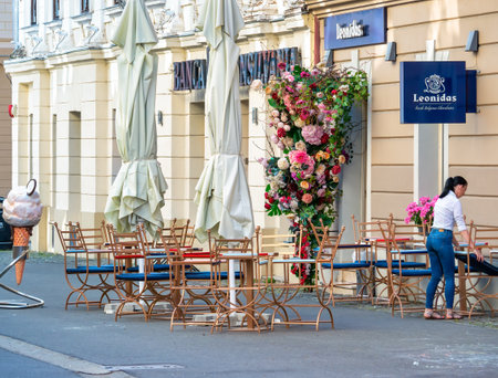 Timisoara, Romania - 06.19.2021:Leonidas Belgian Chocolates shop, store and outdoor terrace cafe in the center of Timisoara.Womana preparing the tables for customers.のeditorial素材