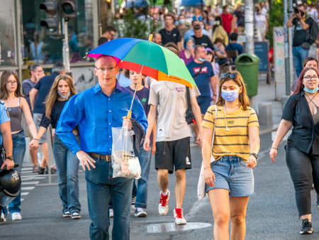 Bucharest, Romania - 08.14.2021: Many people and a man with a colored umbrella attending at LGBTQ Pride parade rally .のeditorial素材
