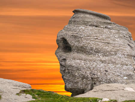 The natural rock formation in the Bucegi Natural Park which is in the Bucegi Mountains of Romania called The Sphinx (Sfinxul) at sunsetの写真素材