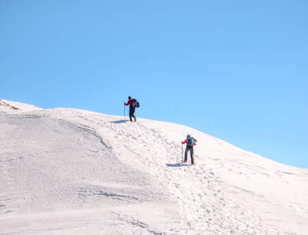 Two Hikers on a trail walking through snow. Winter landscape in Carapathian Mountains, Romania.の写真素材