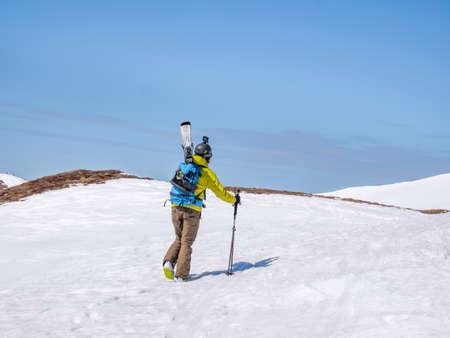 Busteni, Romania - 04.10.2021: Skier in Bucegi Mountains walking on the snow carrying his skisの写真素材