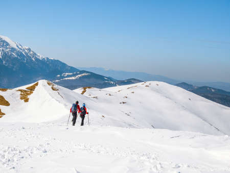 Two Hikers on a trail walking through snow. Winter landscape in Carapathian Mountains, Romania.の写真素材