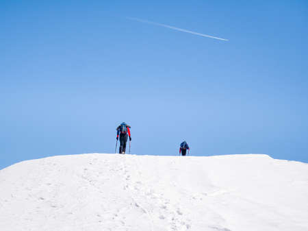 Two Hikers on a trail walking through snow. Winter landscape in Carapathian Mountains, Romania.の写真素材