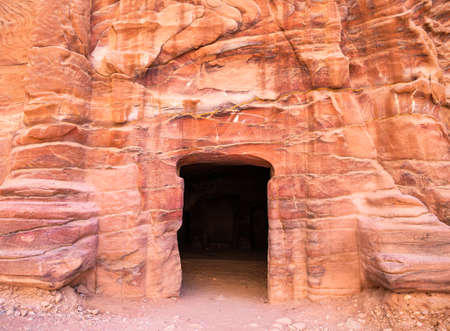 Entrance in a tomb carved in red sand stone located in the ancient city of Petra, Jordan.の写真素材