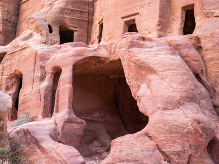 Ancient housing carved in red sand rock in the city of Petra, Jordan. Detail with Tomb of 'Unayshuの写真素材