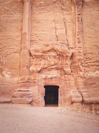 Entrance in a tomb carved in red sand stone located in the ancient city of Petra, Jordan.の写真素材