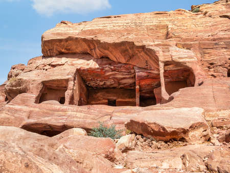 Ancient housing carved in red sand rock in the city of Petra, Jordan.の写真素材