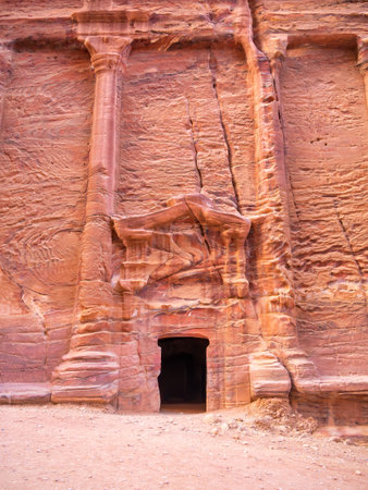 Entrance in a tomb carved in red sand stone located in the ancient city of Petra, Jordan.の写真素材