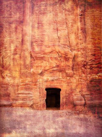 Entrance in a tomb carved in red sand stone located in the ancient city of Petra, Jordan.の写真素材