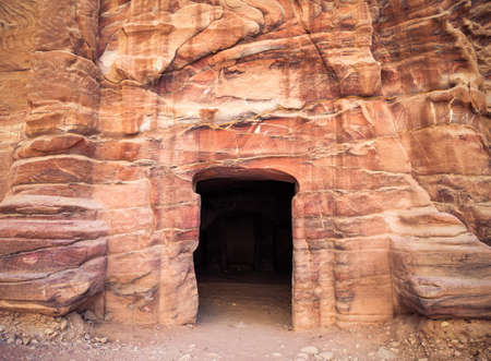 Entrance in a tomb carved in red sand stone located in the ancient city of Petra, Jordan.の写真素材